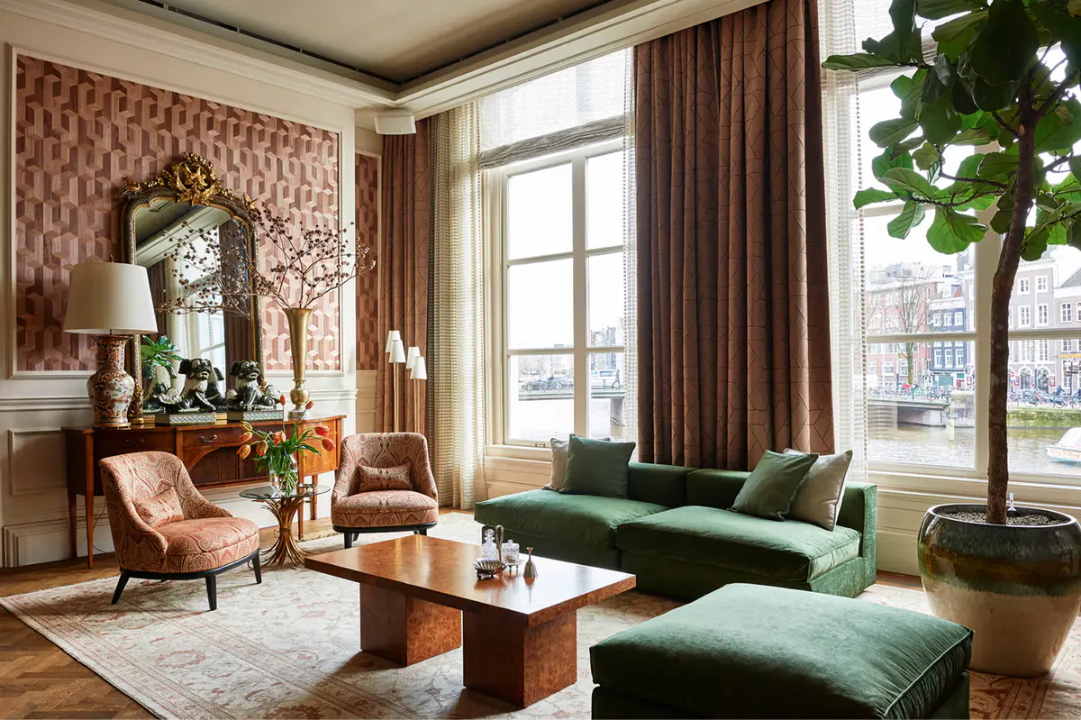 Lounge with green sofa, wooden beams, and two-story arched windows