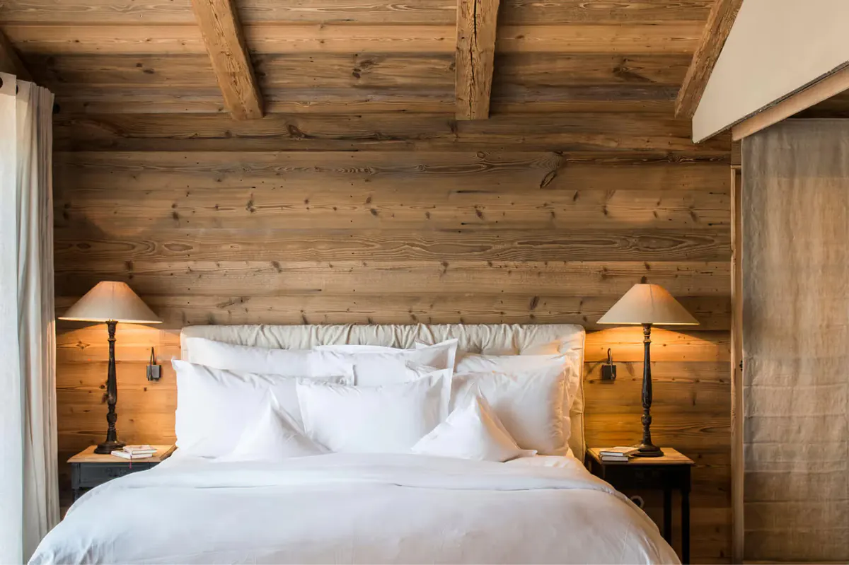 Wooden bedroom with exposed beams and a framed headboard with white bedding