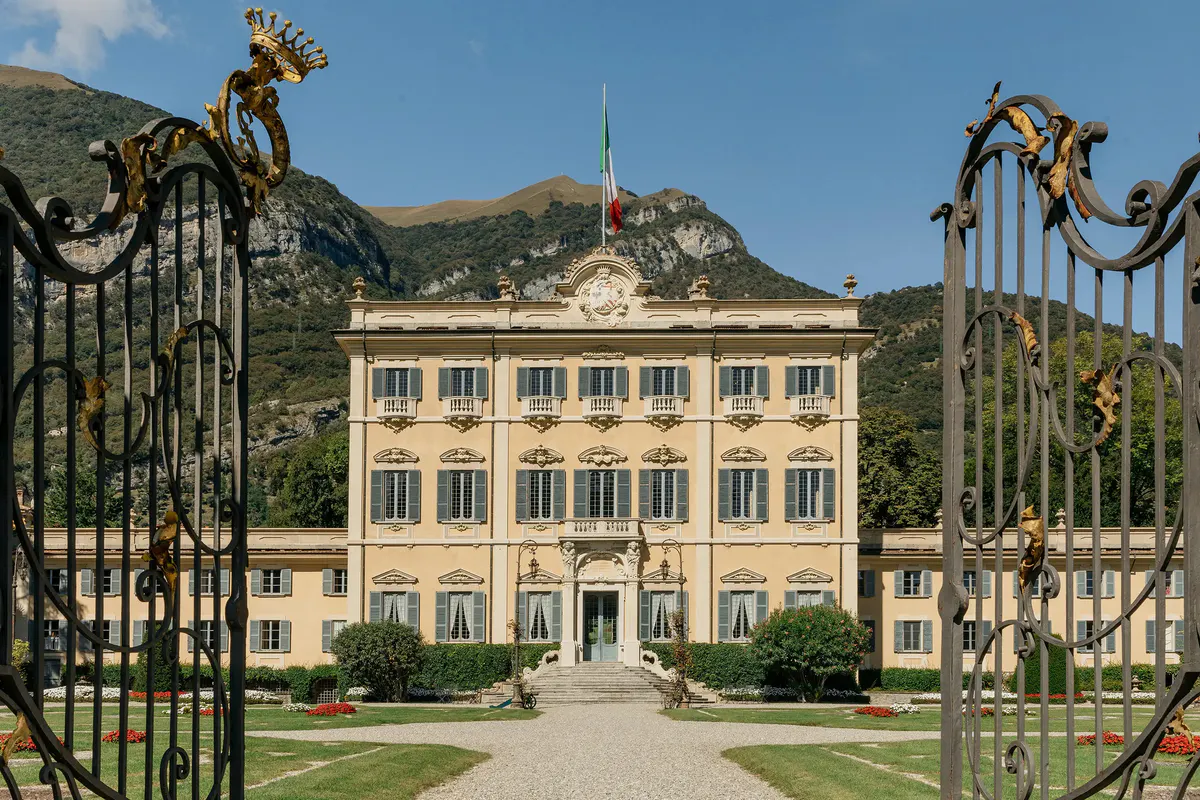 Pale-yellow neoclassical villa with symmetrical design and cypress-lined approach