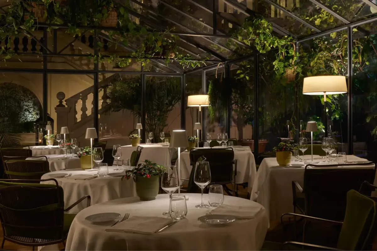 Night dining space with wooden pergola, soft lighting, and white table settings