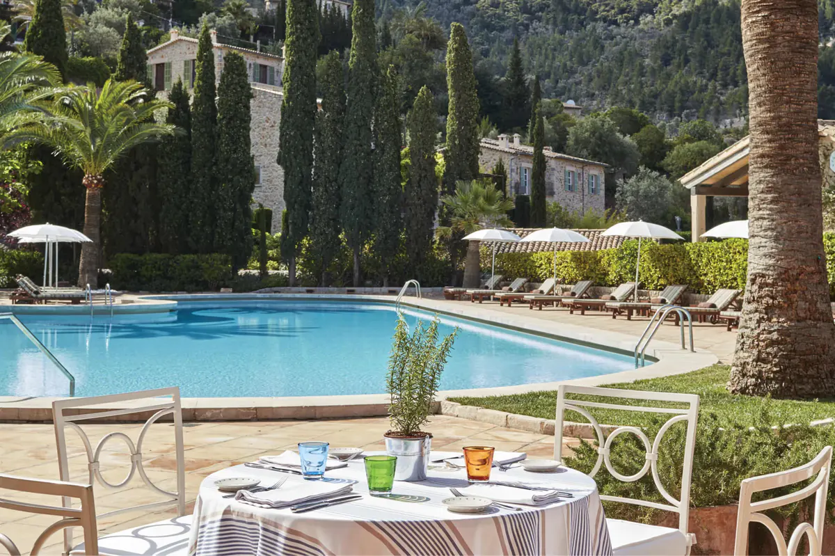 Poolside dining table with Mediterranean valley and building views in afternoon light