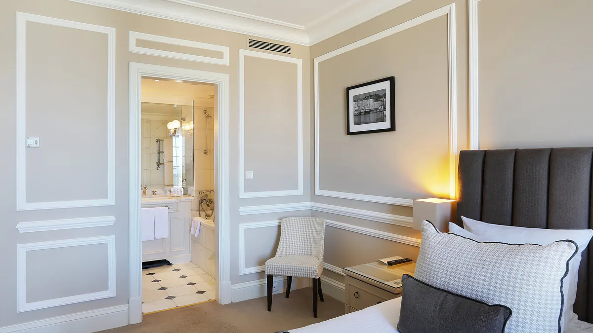 Bedroom entry with white paneling and night-lit lamps beside bed