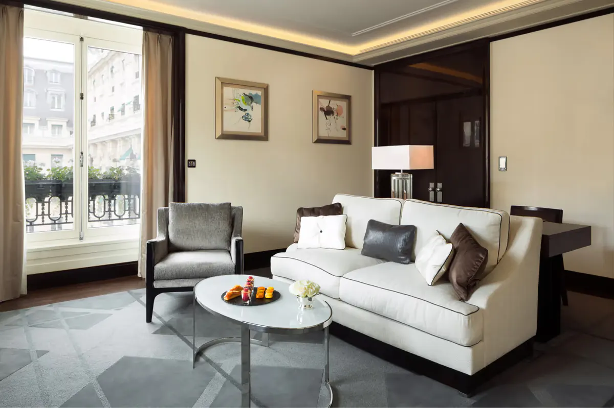 Suite living room with cream sofa, wood accents, louvered closet doors, and tall windows