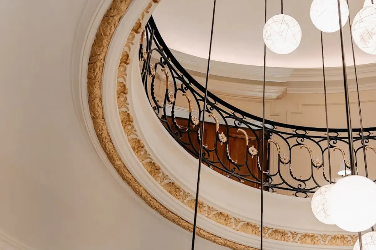 A view looking up at a spiral staircase with ornamental railings and pendant lights