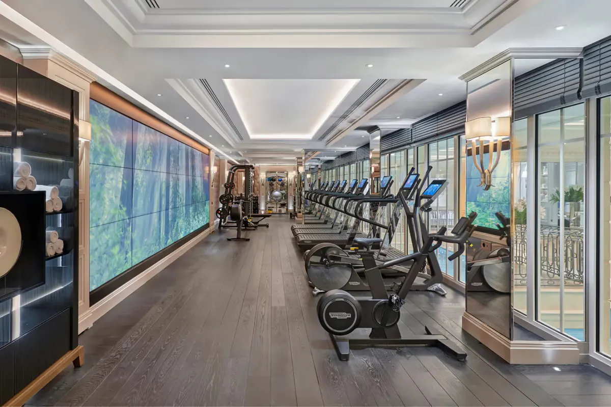 A fitness center with stationary bikes along the windows and modern equipment