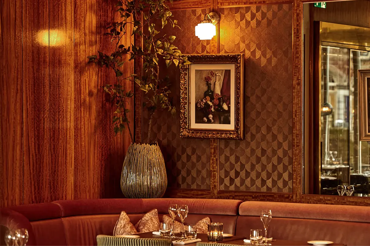 Intimate bar area with mirrored walls, warm wood paneling, and ornamental details