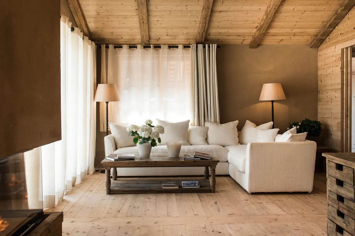 Bedroom suite with cream upholstered furniture and large windows overlooking greenery