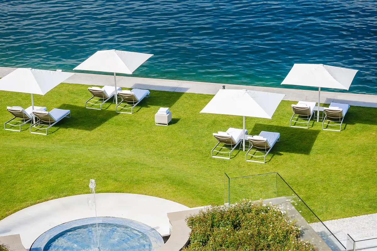 Manicured lawn with white lounge chairs and turquoise water