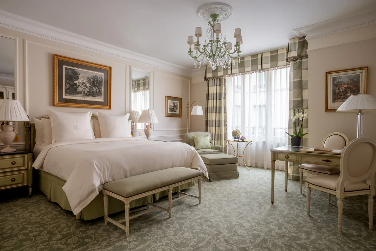 A classical bedroom with gilt accents, arched ceiling details, and a chandelier