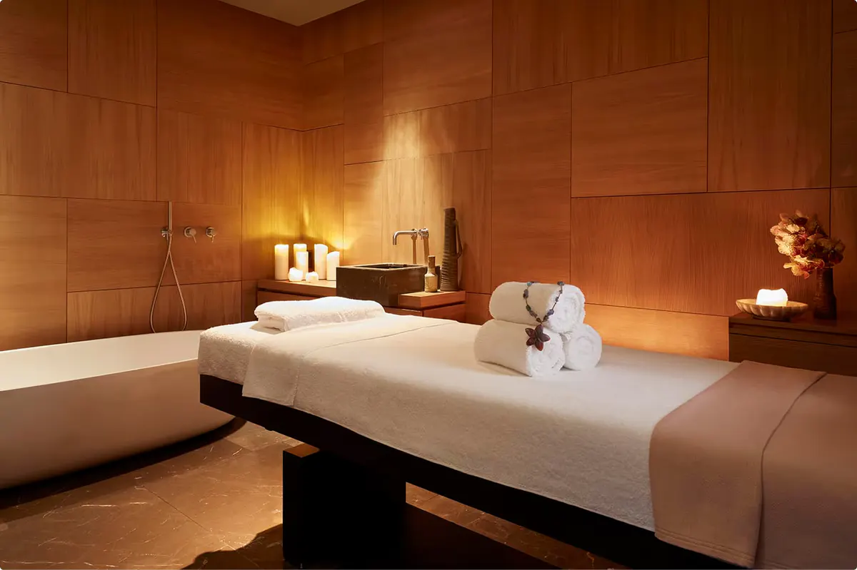 Spa massage treatment room with terracotta tile walls, treatment bed, and ambient lighting