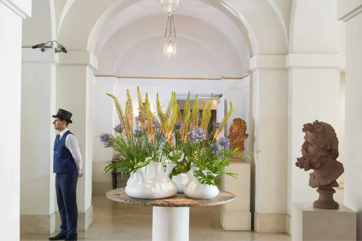 Entrance hall with arched ceiling, tall arrangement of yellow and green flowers in pedestal vase