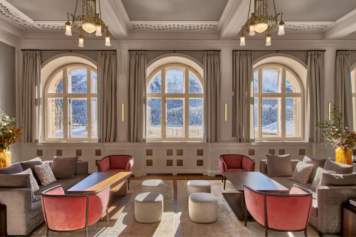 Elegant lounge with arched windows, coral seating, and neutral furnishings in cream tones