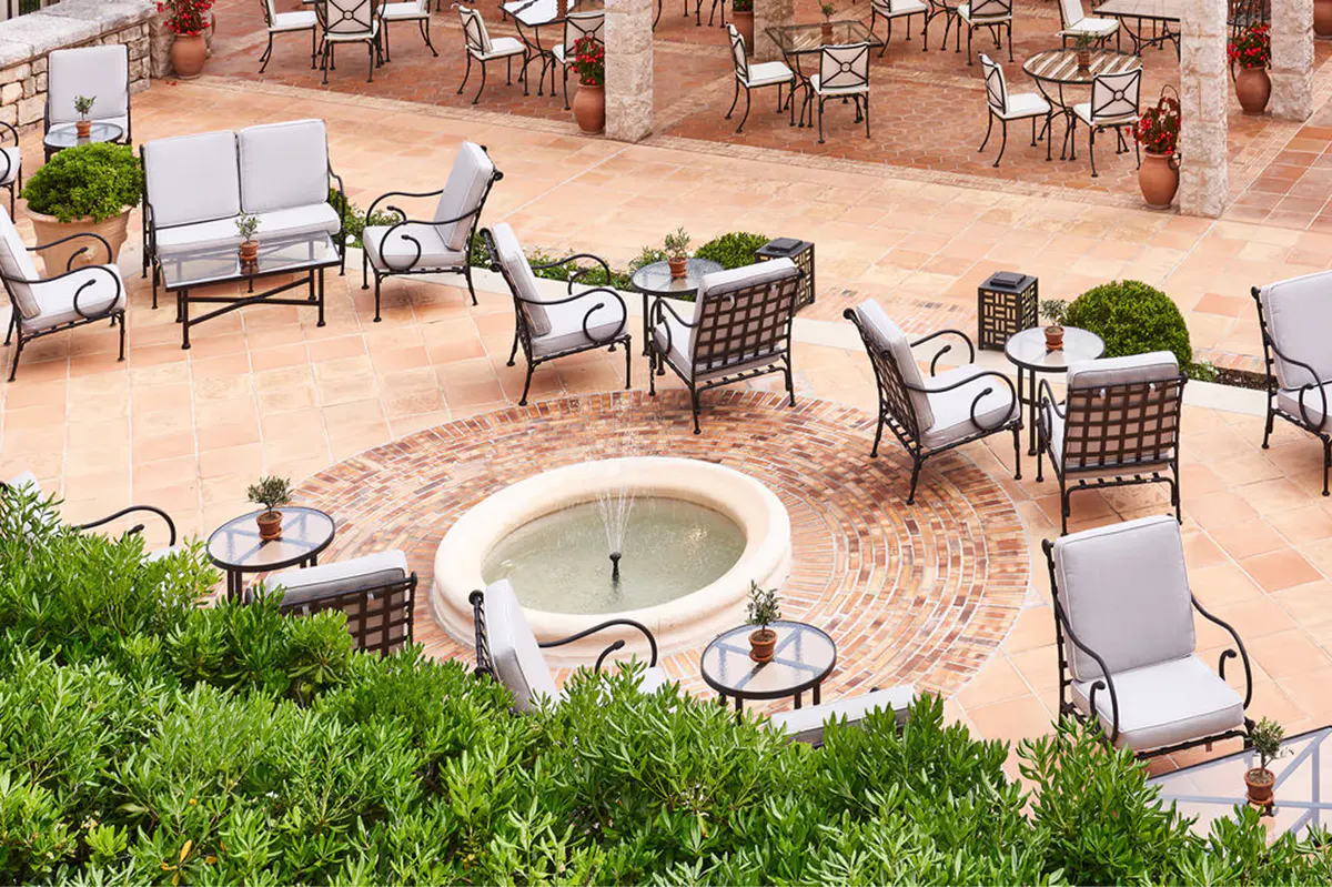 Outdoor terrace with circular fountain and tables under pergola shade