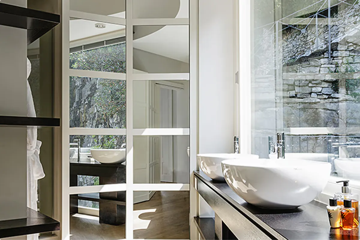 Bathroom with marble surfaces, lit mirror vanity, and minimalist fixtures