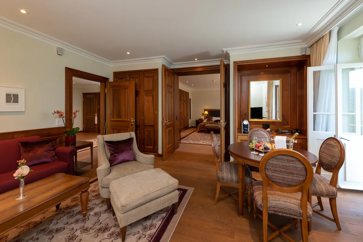 A suite living area with wood parquet floors, sitting furniture, and multiple mountain-view windows