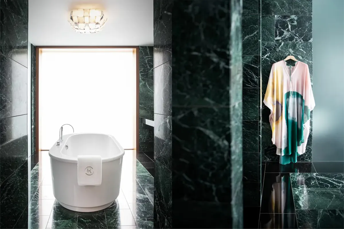 Spa-style bathroom with green marble, soaking tub, and sculptural bath fixtures