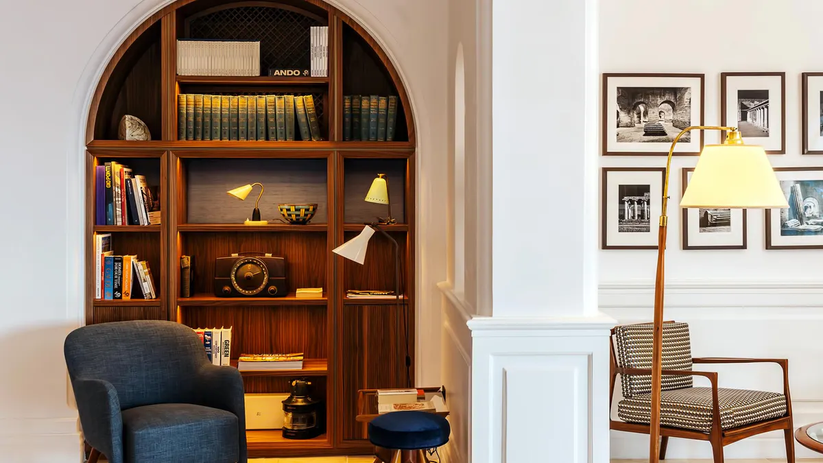 Library nook with arched wooden shelving filled with books and decorative objects