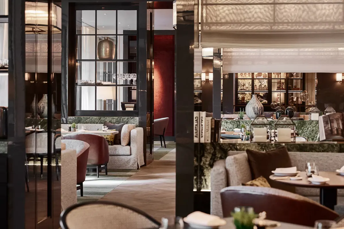Two dining spaces divided by a decorative screen, one red-toned and one neutral with wood details
