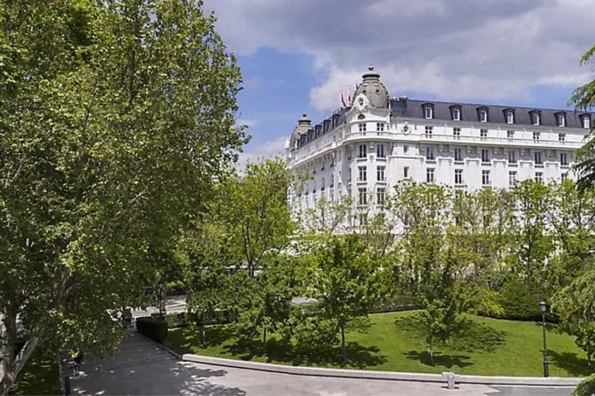 Palatial facade viewed from tree-lined gardens in daylight
