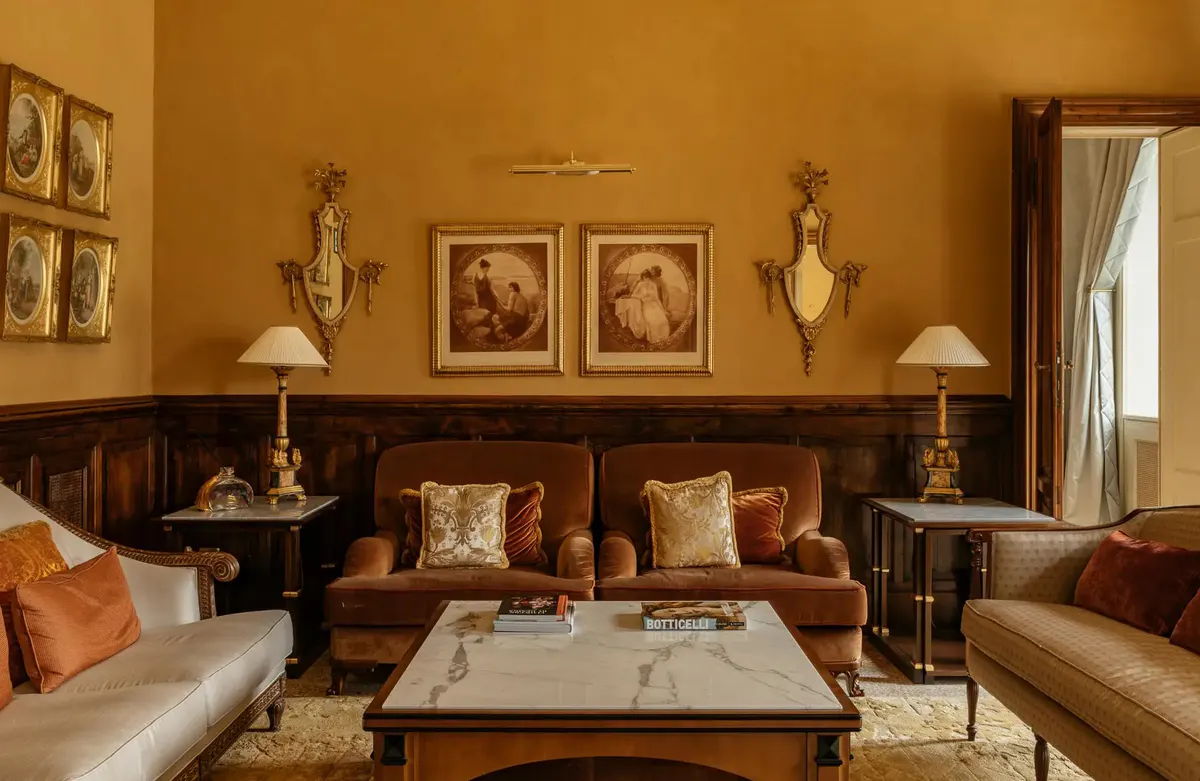 A salon with amber walls, wood cabinetry, dark leather seating, and gilt details