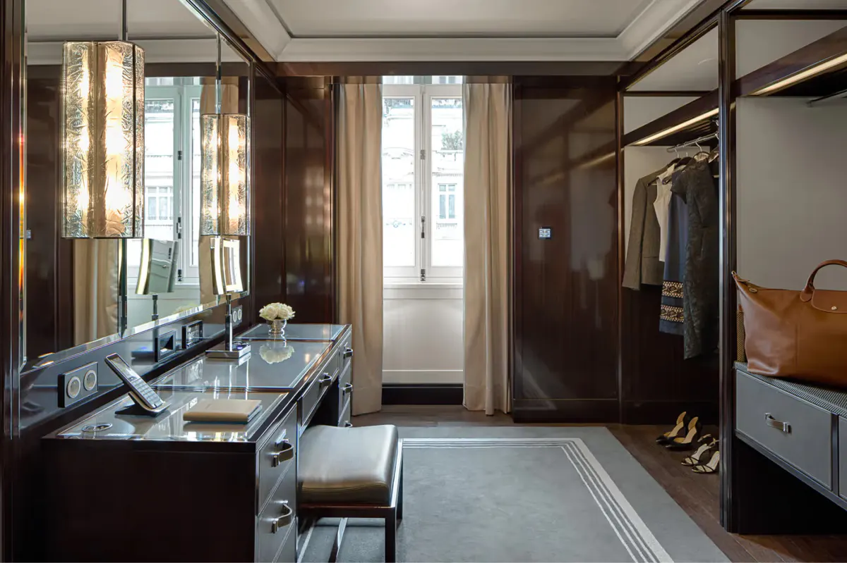 Dressing room with dark wood panels, glass-fronted wardrobe, and a vanity desk