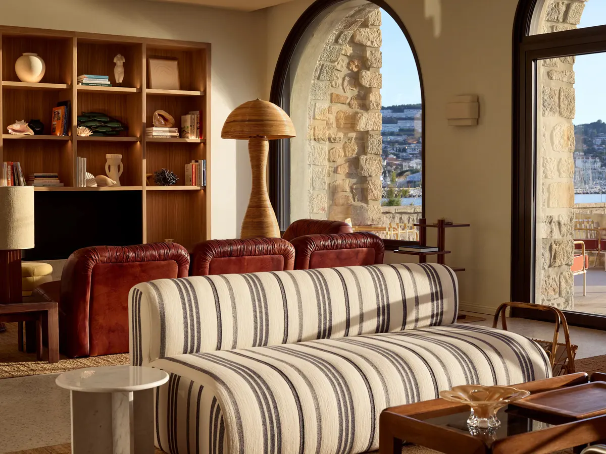 Cognac leather armchairs and a striped sofa face arched windows over the harbor