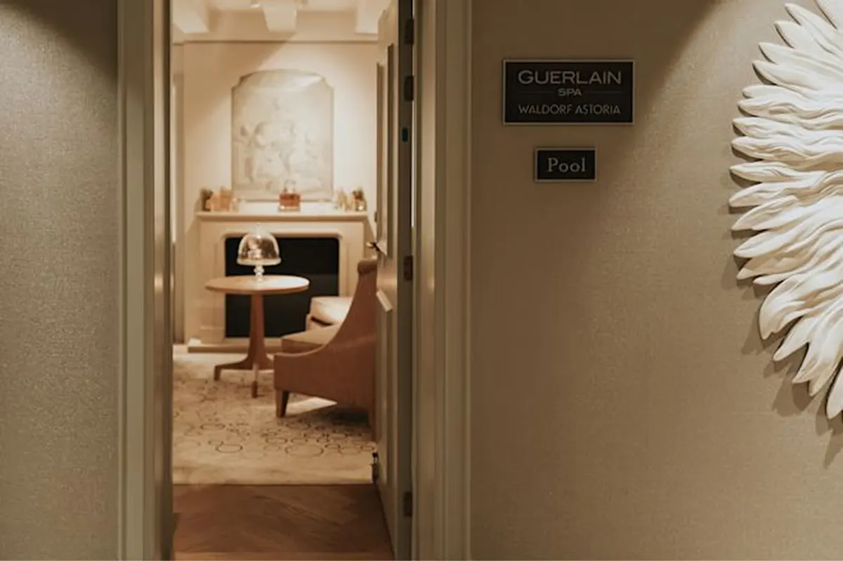 A treatment room entrance with a Guerlain spa sign, minimalist styling, and a white sculptural accent wall