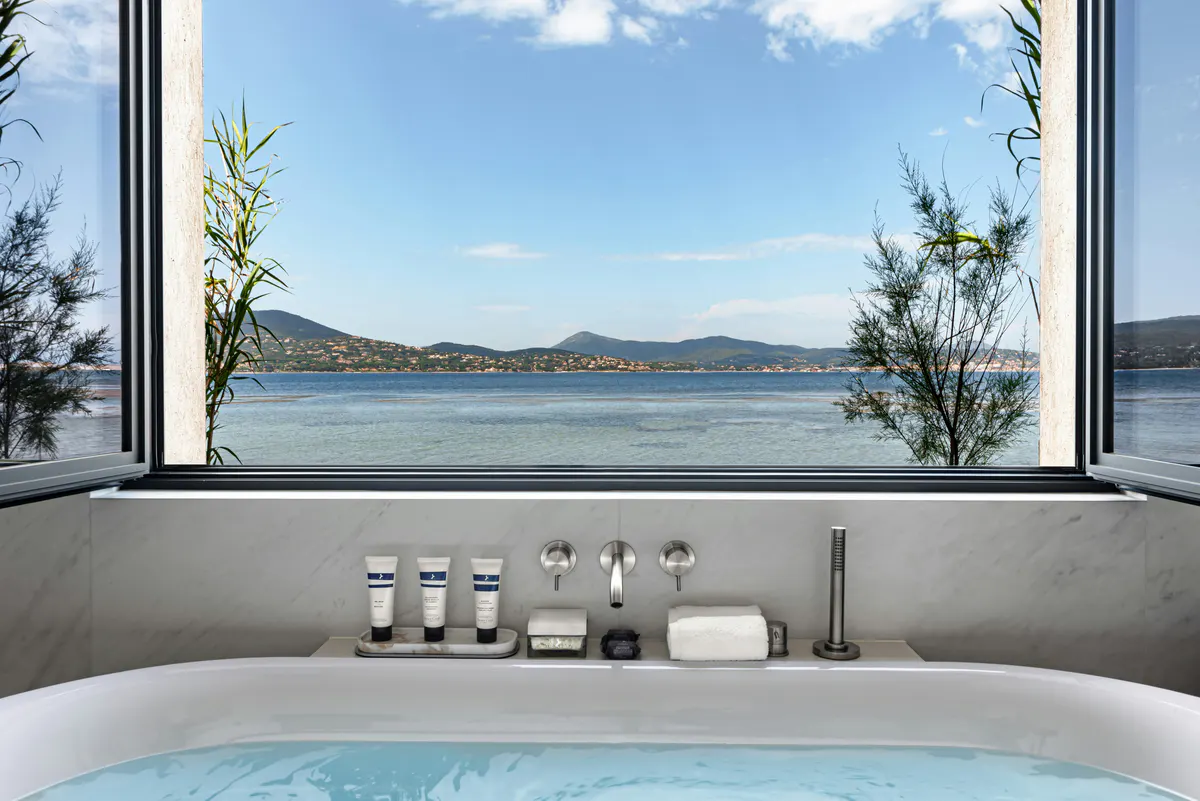 Soaking tub with landscape window framing sea and distant hills