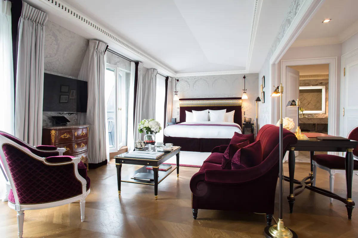 A suite with burgundy velvet armchairs, cream walls, and marble flooring