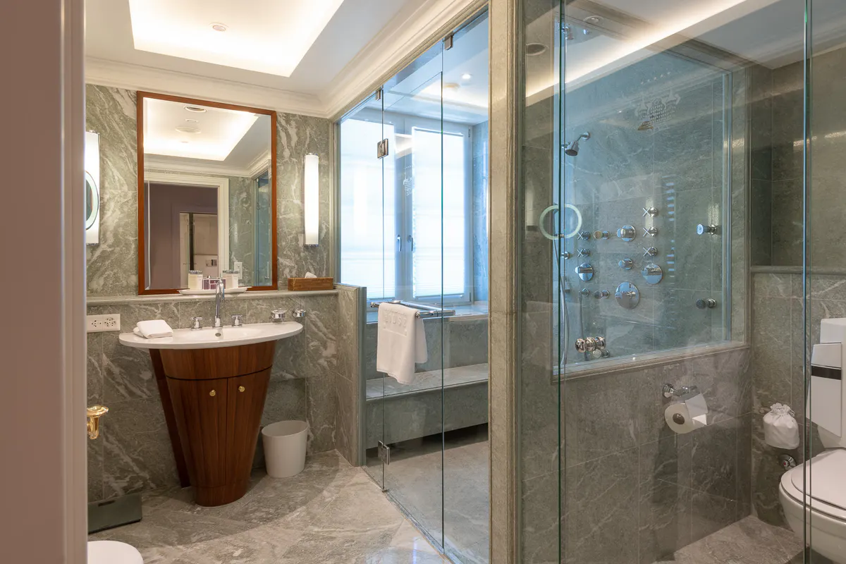 A spa bathroom with wooden vanity, glass shower enclosure, and large windows with alpine light