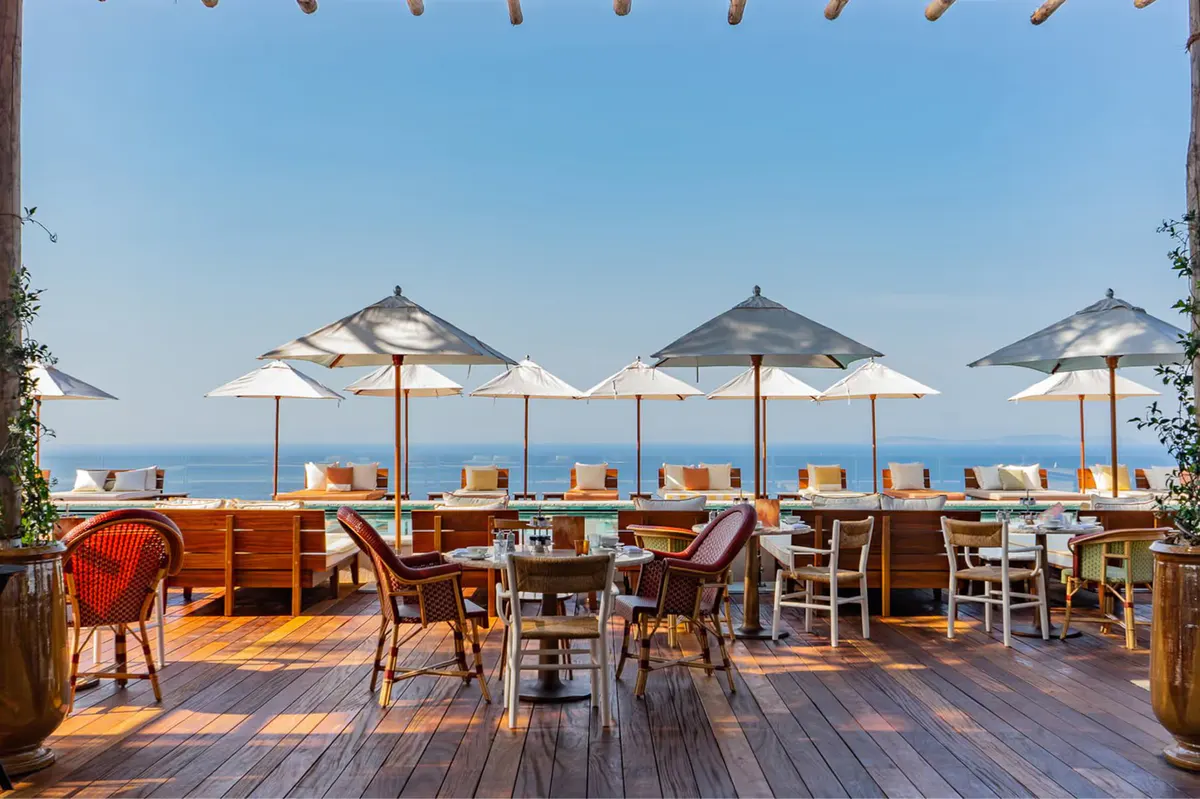 Seaside dining deck with striped umbrellas and tables overlooking sea