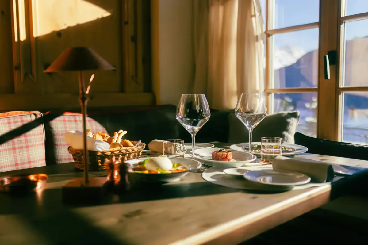A fine dining table set with wine glasses and white linens beside snowy windows