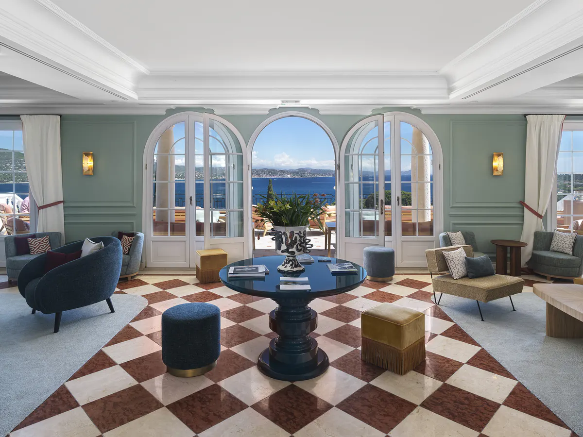Light-filled salon with arched glass doors framing a bay view, marble floor pattern in warm tones