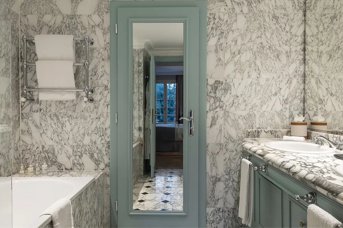 Marble-tiled bathroom with seafoam-green accents and vanity mirror