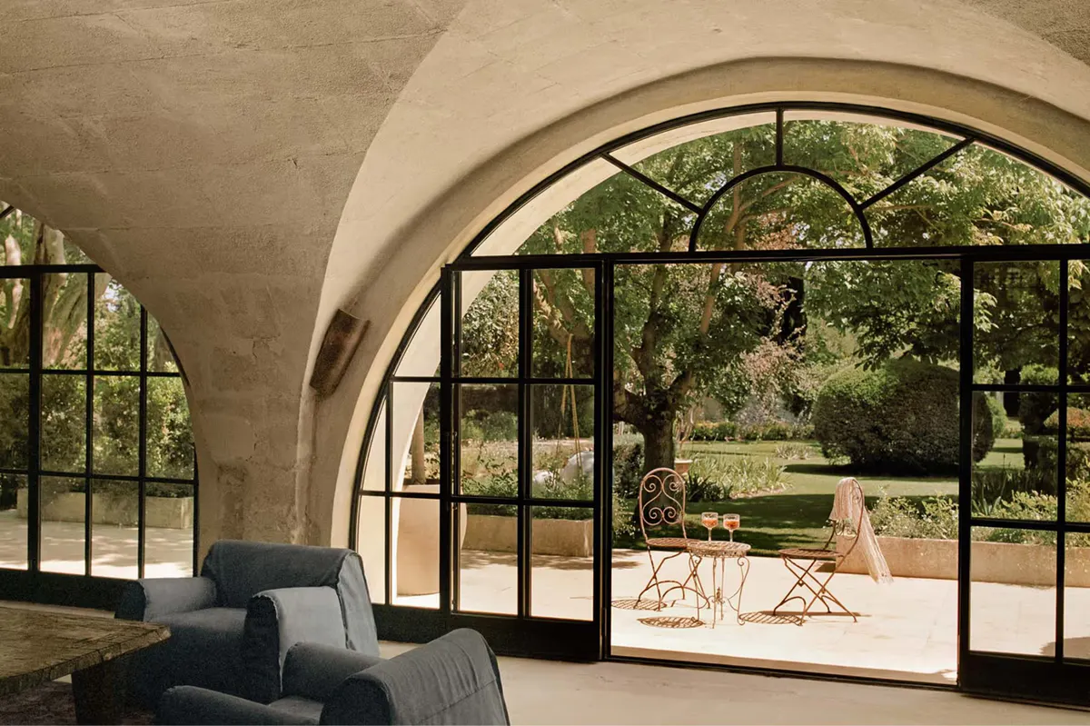 Arched portico with black iron framing opens to manicured terrace and distant landscape