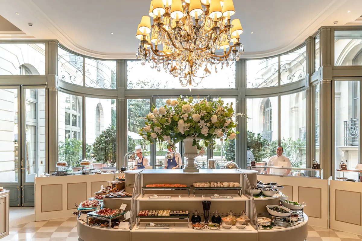 A pastry display counter with flowers, gleaming surfaces, and natural light from large windows