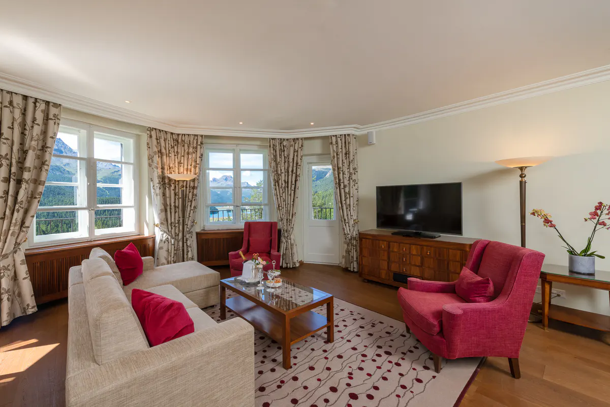 A suite with sitting area, burgundy accent pieces, bay windows, and traditional furnishings