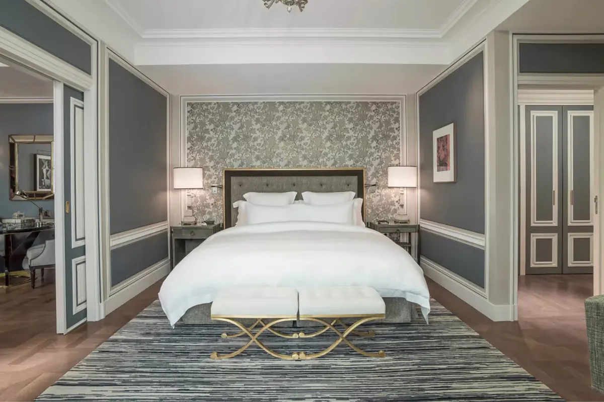 Suite with gray paneled walls, white bed, and coordinating furniture arrangement
