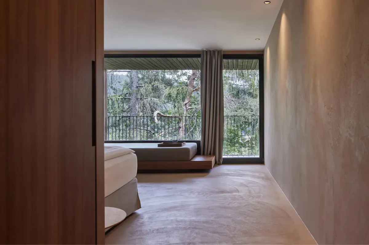 Spacious room with wood-framed glass doors opening to forest views and terraced landscape