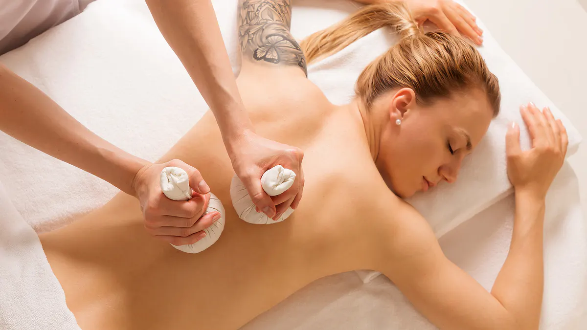 Spa massage treatment with therapist applying thermal stones to guest