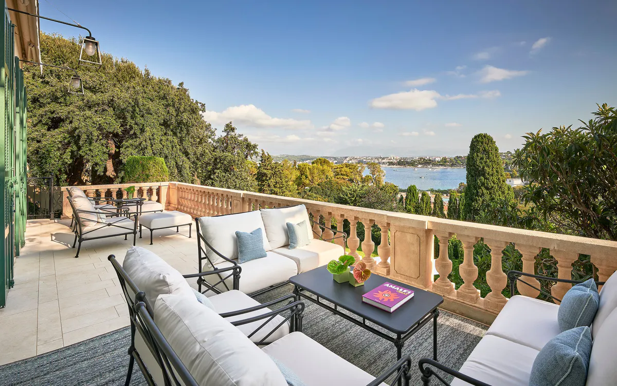 A sea-view terrace with casual seating, soft furnishings, and a stone balustrade overlooking the Mediterranean