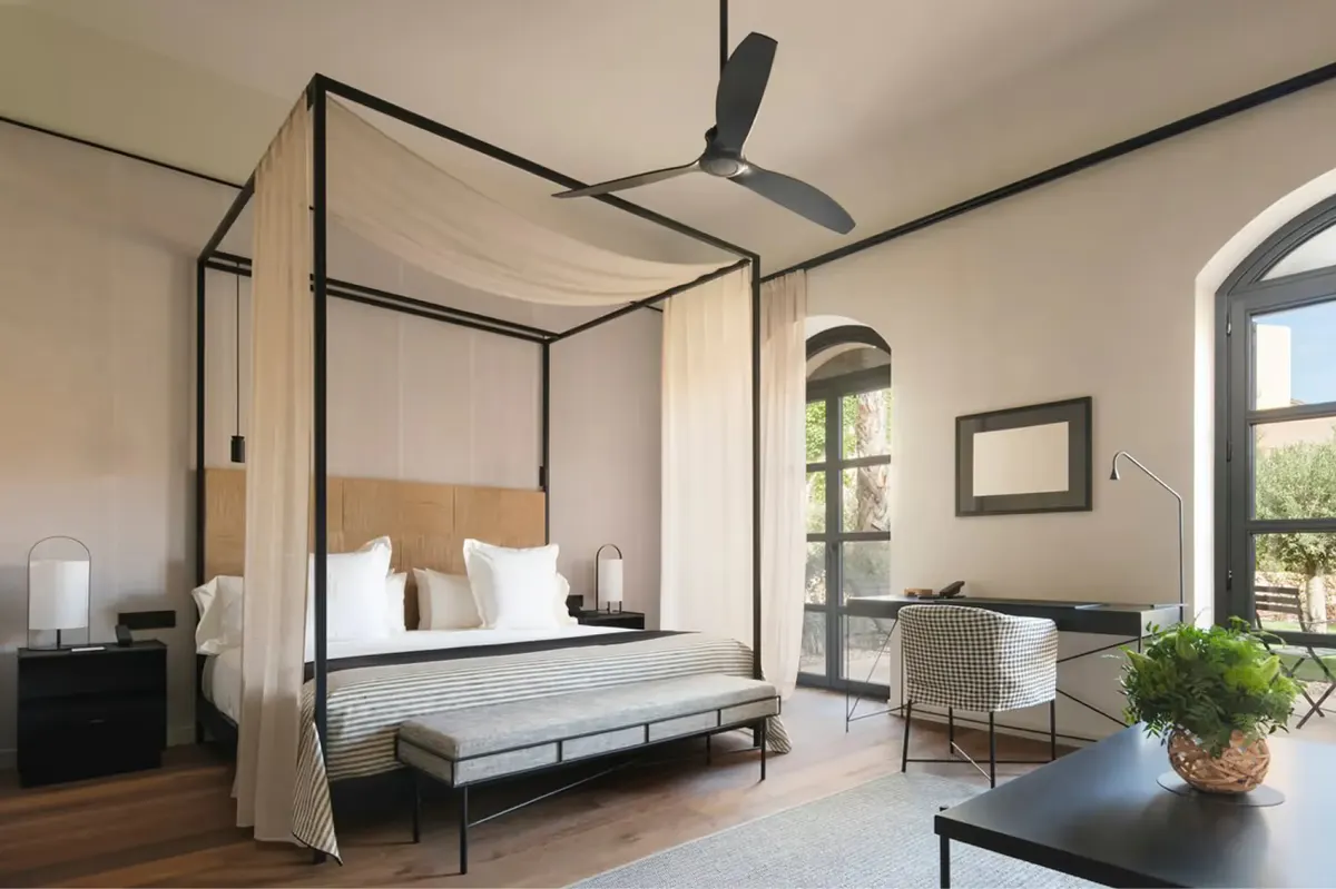 Bedroom with four-poster canopy bed, wooden beams, and garden view