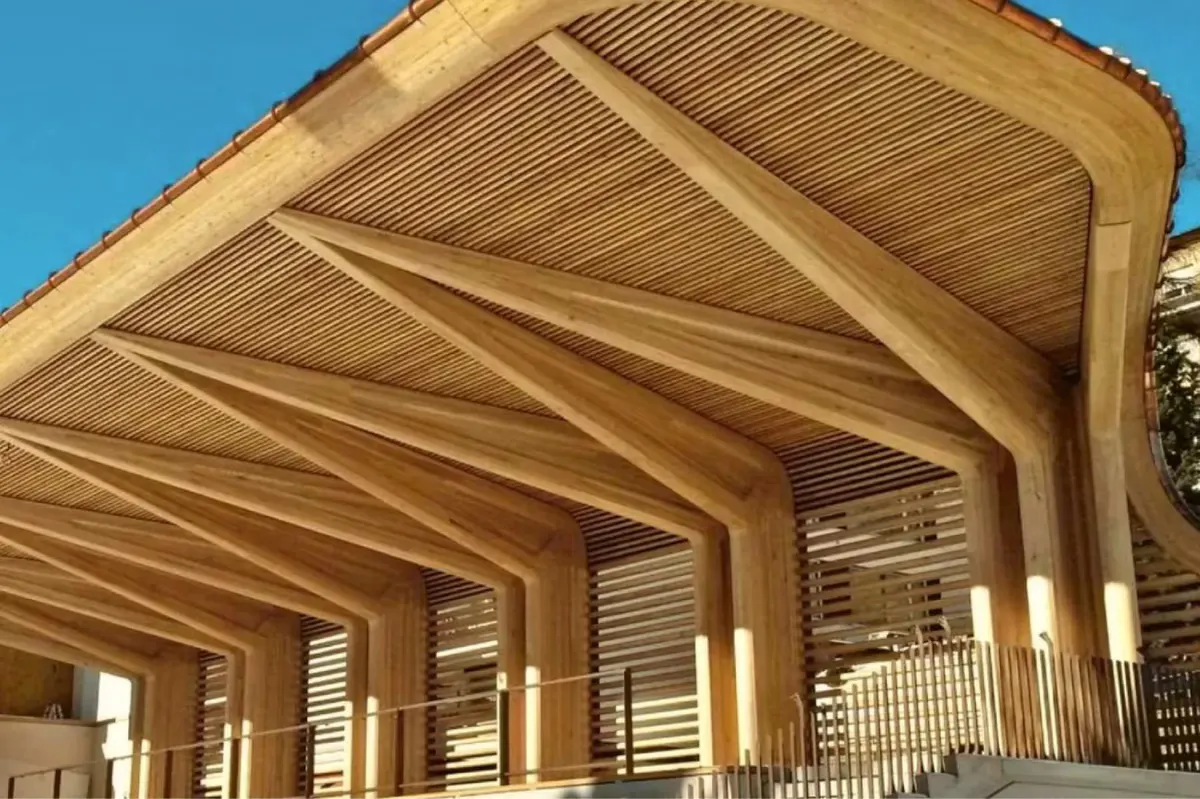 A wooden pergola structure photographed against a bright blue sky
