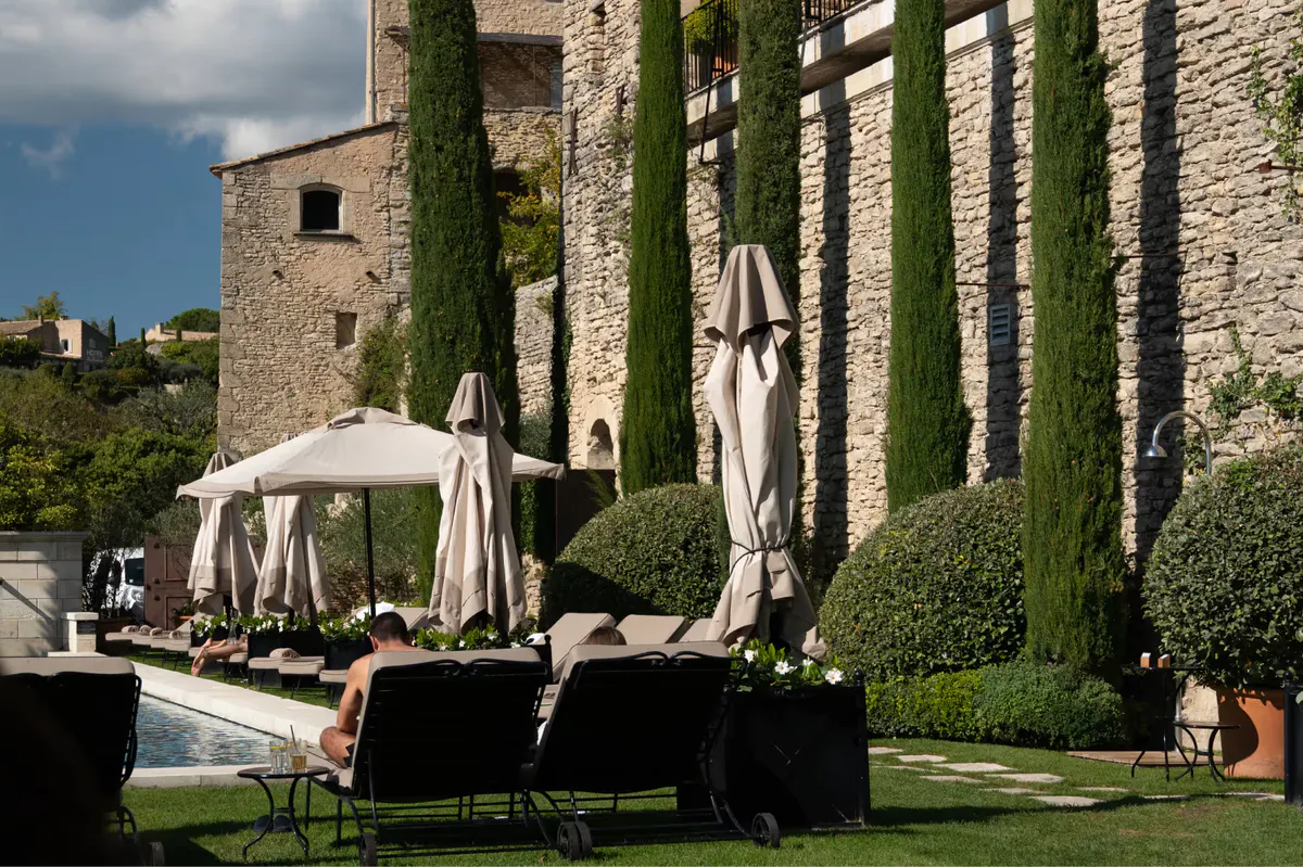Poolside lounge area with stone walls and ivy-covered pergola