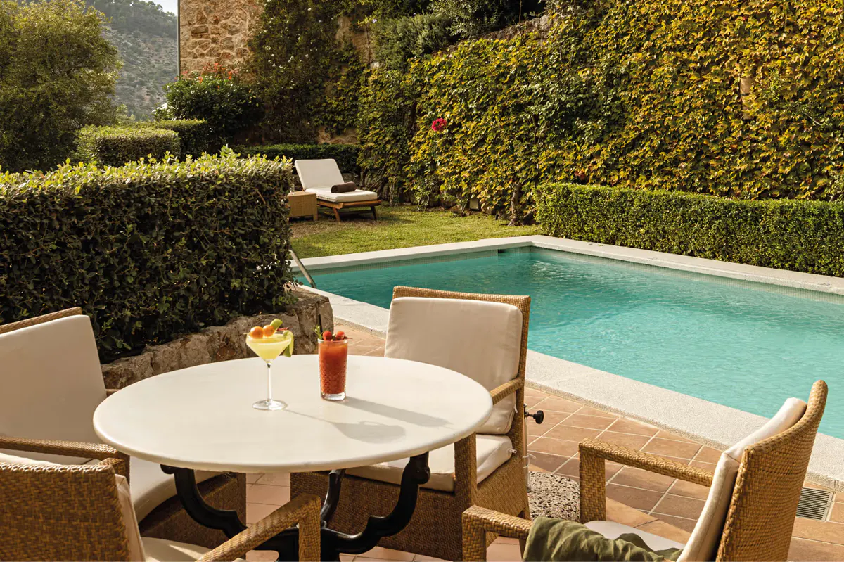 Private terrace with dining table, lounge chair, and panoramic Mediterranean valley view