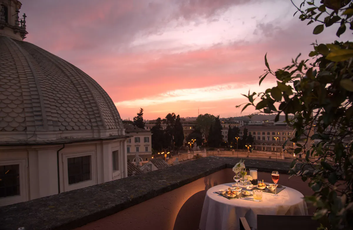 Rooftop table setting at sunset with dome visible and pink sky