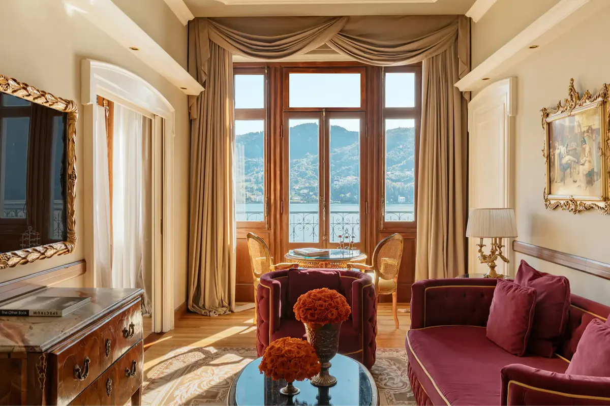 Room with tall windows, burgundy armchair, and furniture positioned toward lake view