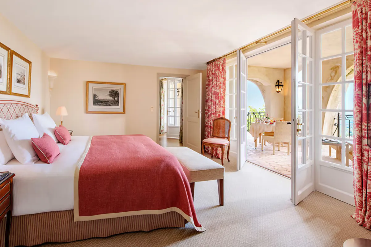 Guest bedroom with burgundy accents, sitting area, and arched windows