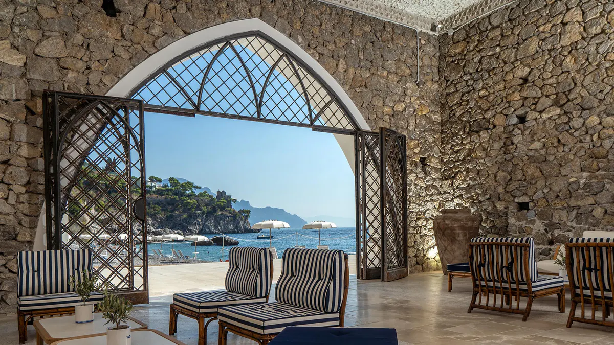 Dining room with arched stone walls and sea views through latticed window opening