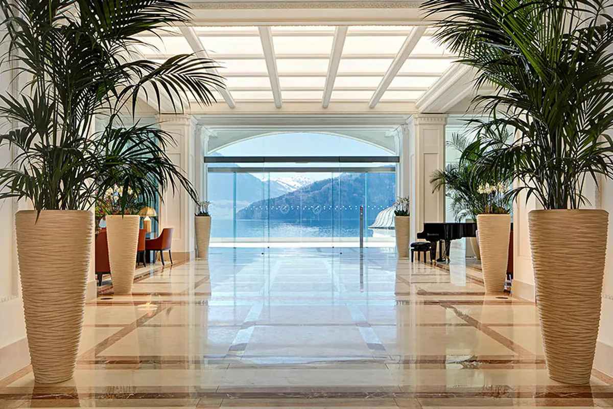 Elegant glass entrance hall with potted palms and lake view